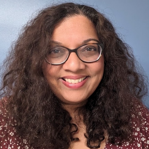 Profile photo. Smiling brown-skinned woman wearing glasses.