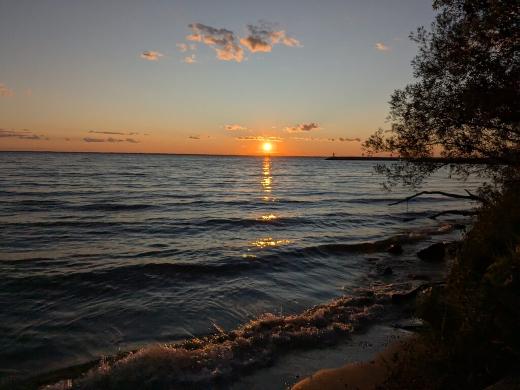 The sun setting over Lake Winnebago in Wisconsin. Soft waves meet the shore.
